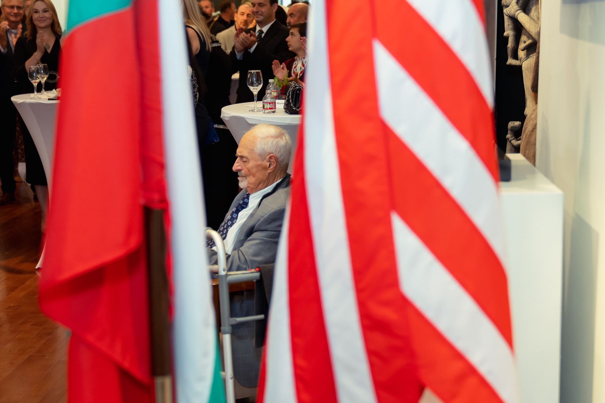 A man in a chair sitting between two flags.